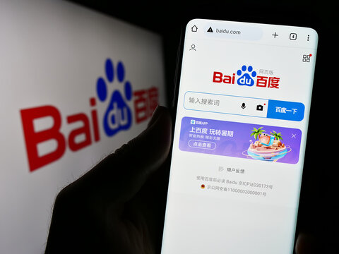 Stuttgart, Germany - 08-15-2023: Person holding cellphone with webpage of Chinese technology company Baidu Inc. on screen in front of logo. Focus on center of phone display.
