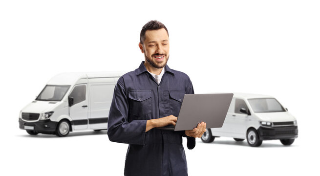 Auto mechanic using a laptop computer in front of vans