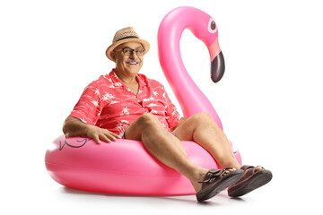 Mature man sitting on a big inflatable flamingo rubber ring