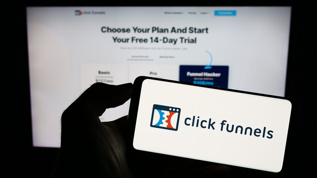 Stuttgart, Germany - 08-17-2023: Person holding cellphone with logo of software company ClickFunnels (Etison LLC) on screen in front of business webpage. Focus on phone display.