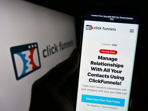 Stuttgart, Germany - 08-17-2023: Person holding cellphone with webpage of software company ClickFunnels (Etison LLC) on screen in front of logo. Focus on center of phone display.