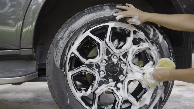 Man washing suv car with sponge in garage.