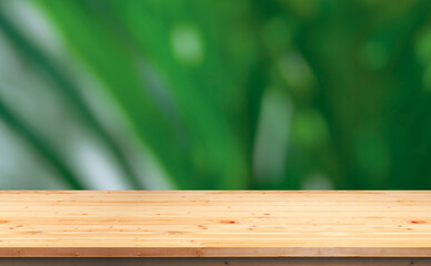 Empty wooden tabletop on blurred outdoor greenery background, suitable for product mockup display presentation