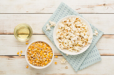 Prepared popcorn with ingredients on wooden background, top view