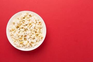 Tasty popcorn in bowl on color background