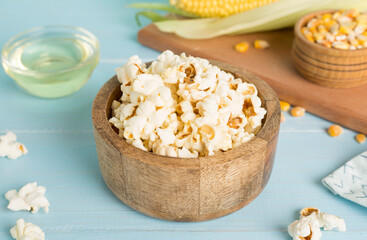 Prepared popcorn with ingredients on wooden table