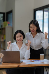 Fototapeta premium Two Asian businesswoman is excited and delighted achieved goal with laptop computer at office.