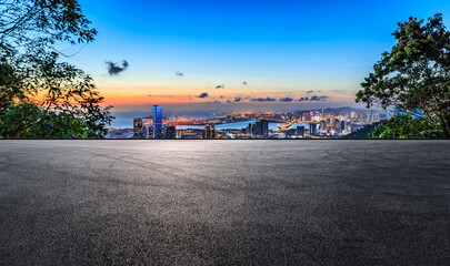 Asphalt road and city skyline with modern buildings at sunset by the sea
