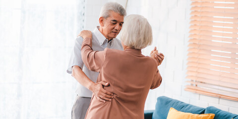 Fototapeta premium Asian happy senior couple having fun and relax dancing together at home, love, romantic elderly mature person or husband and wife lifestyle, aged retirement man and woman family are smiling to dance