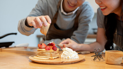 Close-up image of a handsome young Asian man enjoys cooking pancakes with his girlfriend