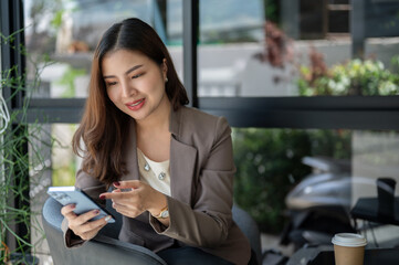 A beautiful Asian businesswoman is using her smartphone while sitting in a coffee shop