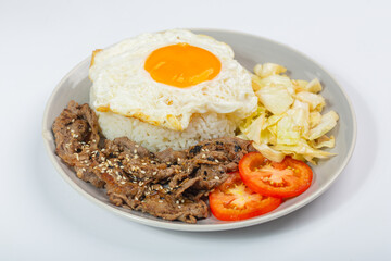 Stir-fried beef with vegetables and fried egg topped with white sesame seeds and tomatoes on a white background.