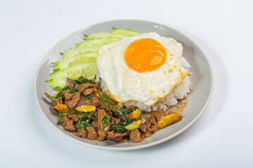 Stir-fried beef with basil leaves, fried egg and cucumber slices on white background