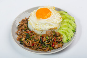 Stir-fried beef with basil leaves, fried egg and cucumber slices on white background