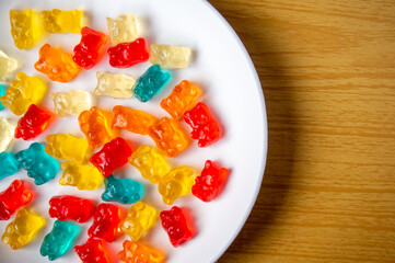 Sweet jelly bear candy on a white plate with a wood pattern background