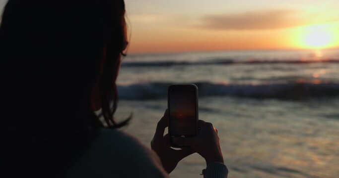 Sunset, photographer and phone with person at beach for social media, relax or vacation. Silhouette, ocean and travel blog with woman and picture on holiday for website, live streaming and influencer