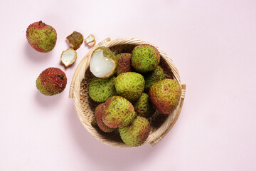 Fresh Ripe Green Lychee Fruit and Peeled lychee on a Rattan Bowl.