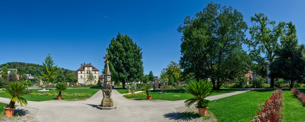 Fototapeta na wymiar Panoramafoto im Stadtgarten von Schwäbisch Gmünd mit Beeten, Weg, Sonnenuhr und stahlblauem, wolkenlosem Himmel bei Sommerwetter