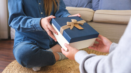 Closeup image of a couple women receiving and giving a gift box to each other