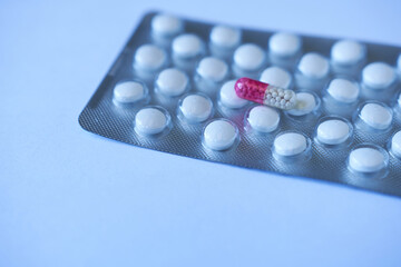 Medicine pills in blister pack on blue background. Focus on foreground, soft bokeh.