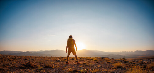 An active young man feels free. A confident man stands on a mountain against the background of a...
