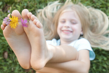Child feet on green grass, barefoot little girl on meadow, countryside lifestyle, concept of grounding and connecting with nature