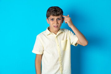 Beautiful kid boy wearing casual shirt pointing unhappy at pimple on forehead, blackhead  infection. Skincare concept.