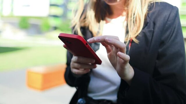 Smiling businesswoman using her phone outdoors. Small business entrepreneur looking at her mobile phone and smiling while communicating with her office colleagues. High quality 