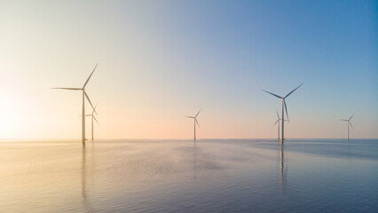 offshore windmill park, windmill park in the ocean aerial view with wind turbine Flevoland Netherlands Ijsselmeer. Green energy during sunset