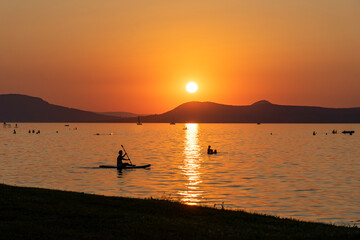 Lake Balaton at sunset with kayaking man silhouette and the north part mountains in the background