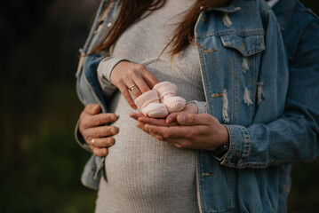 Concept of pregnancy: hands hold big round female stomach with childbirth expectations, fine art style photo selective focus