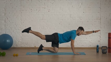 Man fitness instructor in sportswear doing back body strengthening exercise for online class at home.