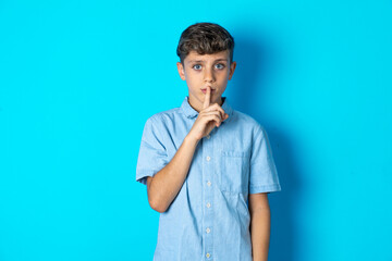 Beautiful kid boy wearing  casual blue shirt  looking unhappy and angry showing rejection and negative with thumbs down gesture. Bad expression.