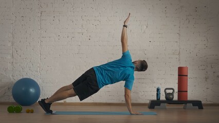 Closeup shot. Man coach in sportswear doing active elbow plank at the home studio.