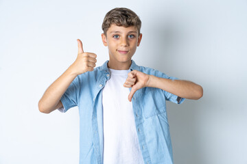 Beautiful kid boy wearing  casual clothes showing thumbs up and thumbs down, difficult choose...