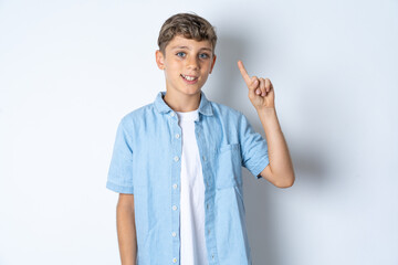 Beautiful kid boy wearing  casual clothes  showing and pointing up with finger number one while smiling confident and happy.