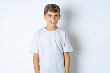 Portrait of dissatisfied Beautiful kid boy wearing grey casual t-shirt smirks face, purses lips and...