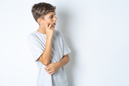 Astonished Beautiful kid boy wearing grey casual t-shirt looks aside surprisingly with opened mouth.