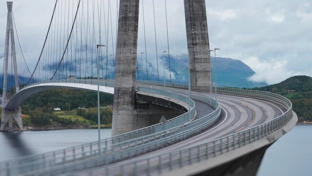 Cars and trucks pass along the curves of the Halogaand Bridge above the fjord. Tight parallax shot.