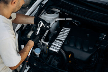 The man holds socket head for a wrench for tightening and unrolling nuts and bolts. A set of adapters. Work in a car repair shop, service, garage.