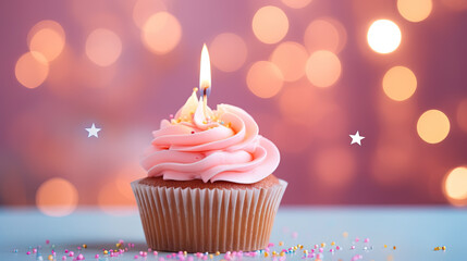Pink birthday muffin with candle and bokeh lights.