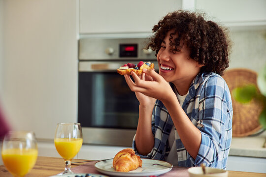 Happy African American teenage boy enjoying a healthy breakfast at home.