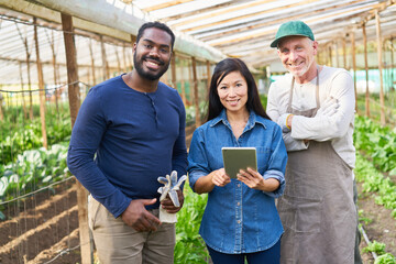 Smiling female farmer standing with colleagues in farm