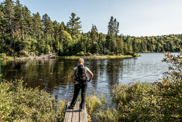 Fototapeta na wymiar Girl hiking in the Forest near lake in La Mauricie National Park Quebec, Canada on a beautiful day
