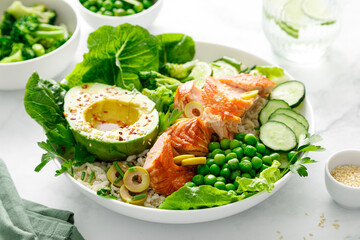 Fototapeta premium Salmon avocado bowl with broccoli, green peas, rice and fresh salad. Healthy food, top view