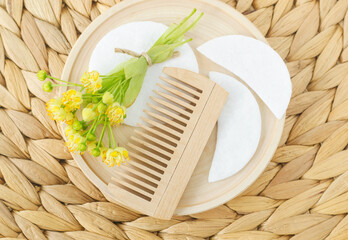 Wooden hairbrush and linden (tilia, basswood, lime tree) flowers. Natural hair care, homemade spa and beauty treatment recipe.