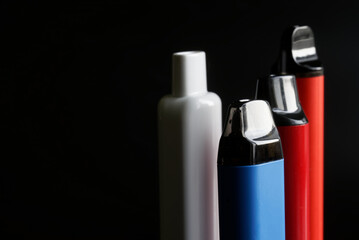 Mouthpieces of modern multi-colored electronic cigarettes on a black background. Copy space. Photo. Selective focus.