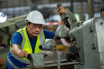 Elderly male worker wear hardhat working at machine in factory. Man technician control metalwork lathe industrial. work factory industrial concept.