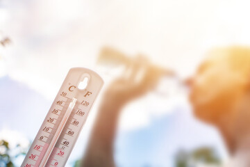 Man drinking water in extreme heat, Thermometer in summer day shows or indicate high temperature,