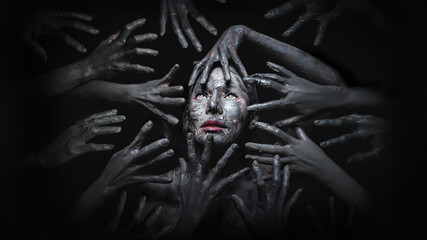 Halloween concept of fancy makeup of scary witch face surrounded by devil hands in the dark background